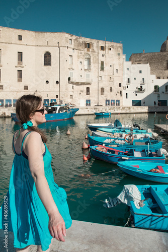 Woman with a blue dress in the picturesque marina of Monopoli, a a little village in south Italy in summer © Laura
