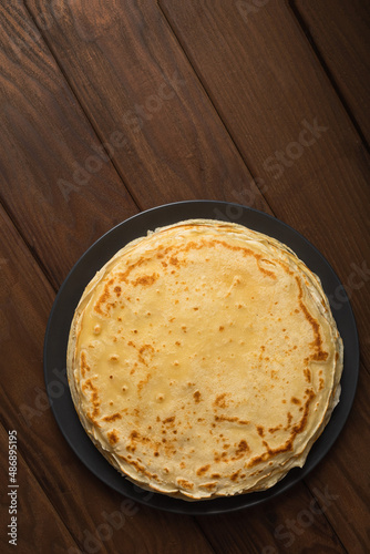 Pancake on the black plate on wooden table. Top view