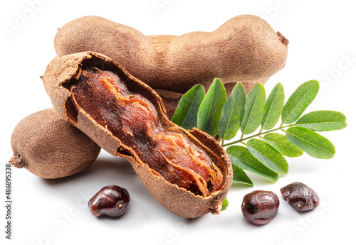 Ripe tamarind fruit, leaves and some tamarind seeds isolated on white background. photo