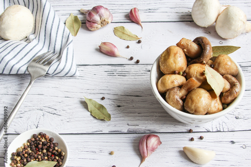 Pickled mushrooms with spice in bowl on the wooden background. Champignons marinated. Marinated mushrooms with garlic, black pepper and bay leaf. Pickled mushrooms with spice in bowl on the wooden background. Champignons marinated. Marinated mushrooms with garlic, black pepper and bay leaf.