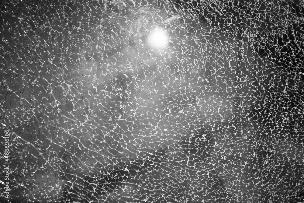 Obraz premium Cracked window glass behind which is the night sky with clouds and the moon. Cracked porthole of a spaceship, behind which you can see space and the sun.
