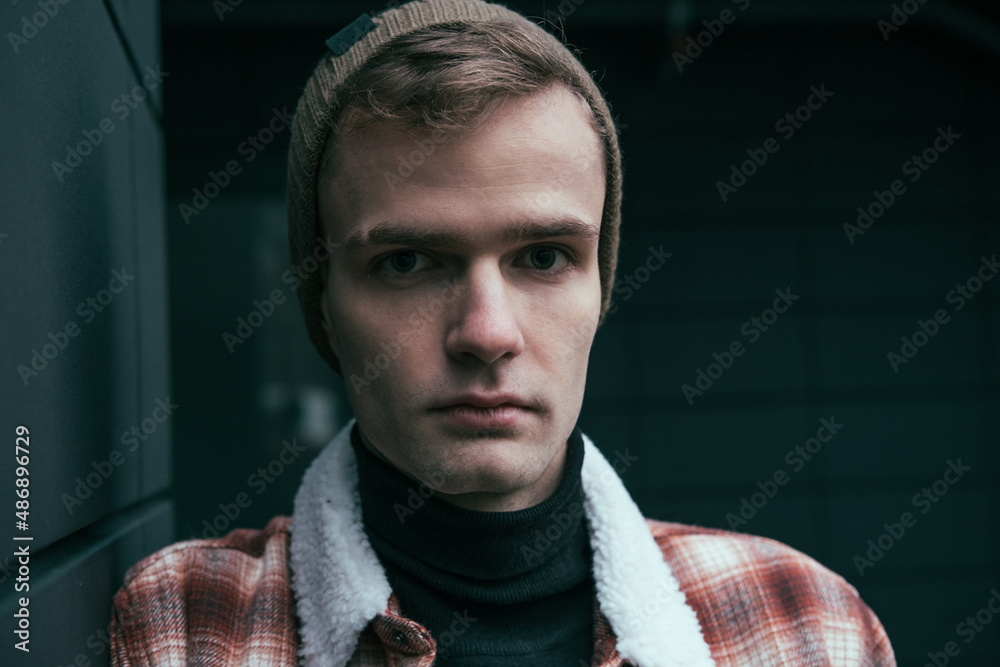 street portrait of a stylish sad young guy, dressed in a hat and jacket