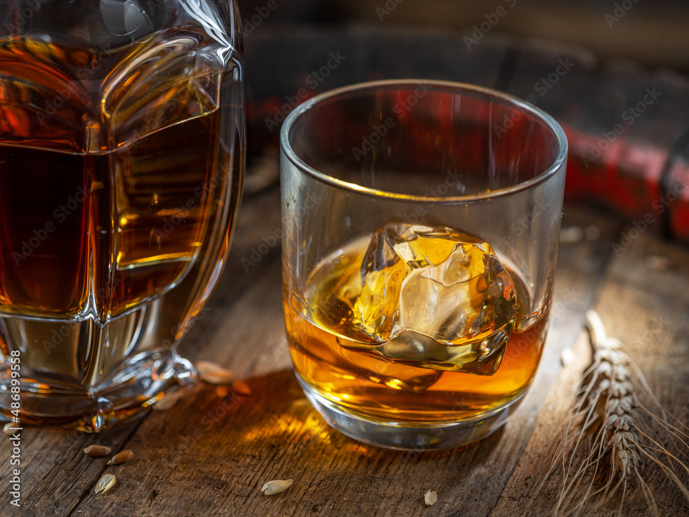 Carafe of whisky and glass of whisky on old wooden cask at the dark background. Carafe of whisky and glass of whisky on old wooden cask at the dark background.
