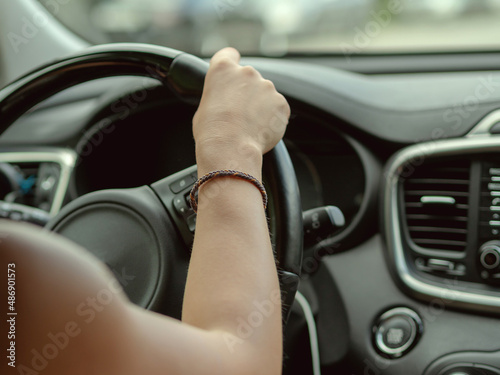 A woman's hand holds the steering wheel in the car. Car driving. Soft focus