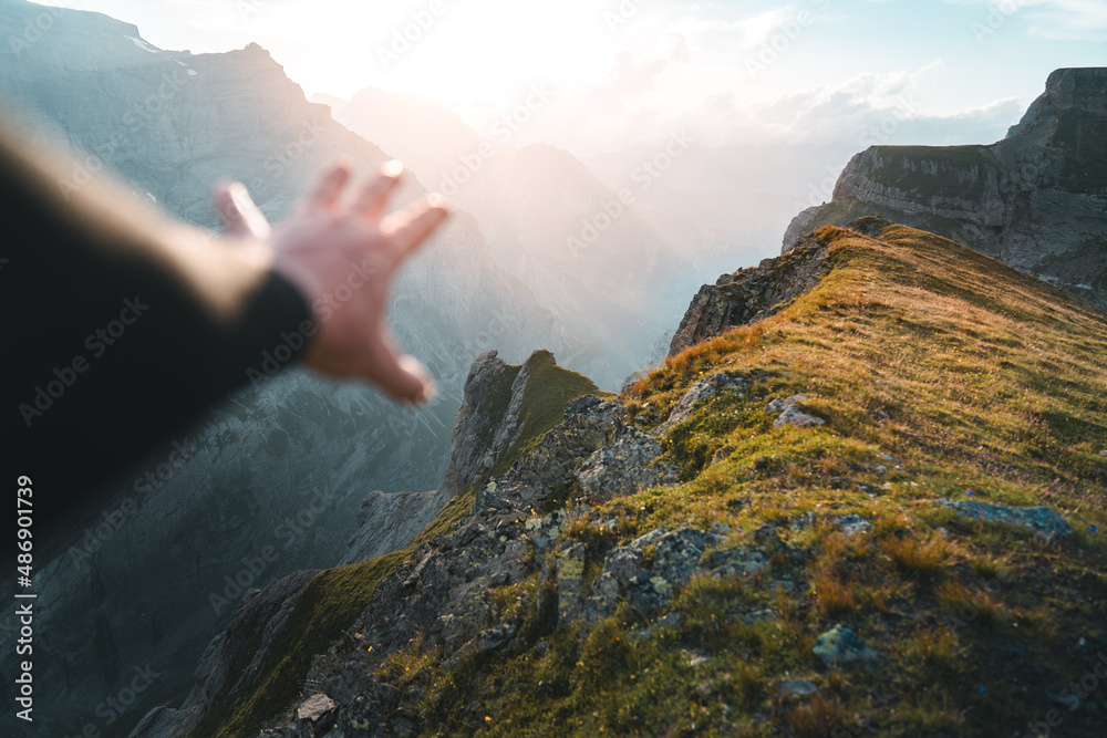 Obraz premium Hand reaching out to touch the warm rays of sunshine. Mind, body, spirit, and freedom in nature concept. Survival, travel and lifestyle hiking concept