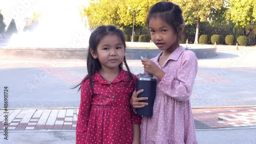Slow motion scene of  6-year-old Asian girl shares water with friends to eat, dispensation, share 