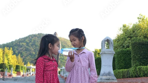 Slow motion scene of  6-year-old Asian girl shares water with friends to eat, dispensation, share 