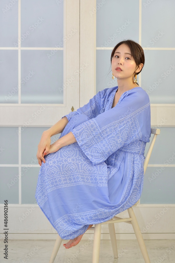 白い窓を背景に椅子に座りくつろぐドレスを着た若い女性 白い窓を背景に椅子に座りくつろぐドレスを着た若い女性
