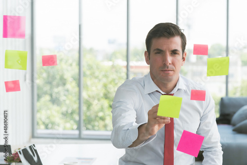 Businessman take notes at colorful chart on glass board is using the idea at his office, in the evening time.