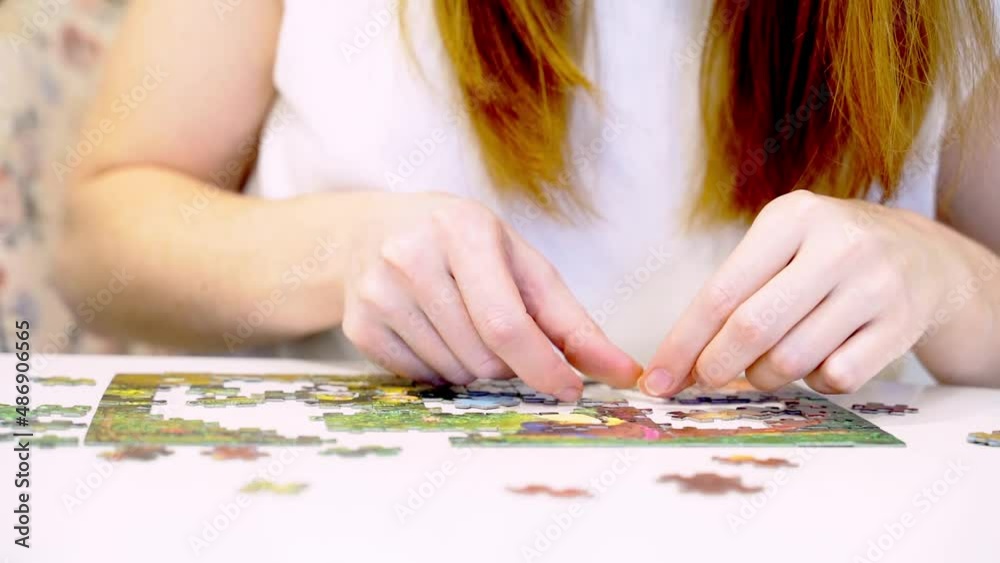 Girl collects puzzles. Board game - puzzle. Lays out puzzles on the table. Girl collects puzzles. Board game - puzzle. Lays out puzzles on the table.