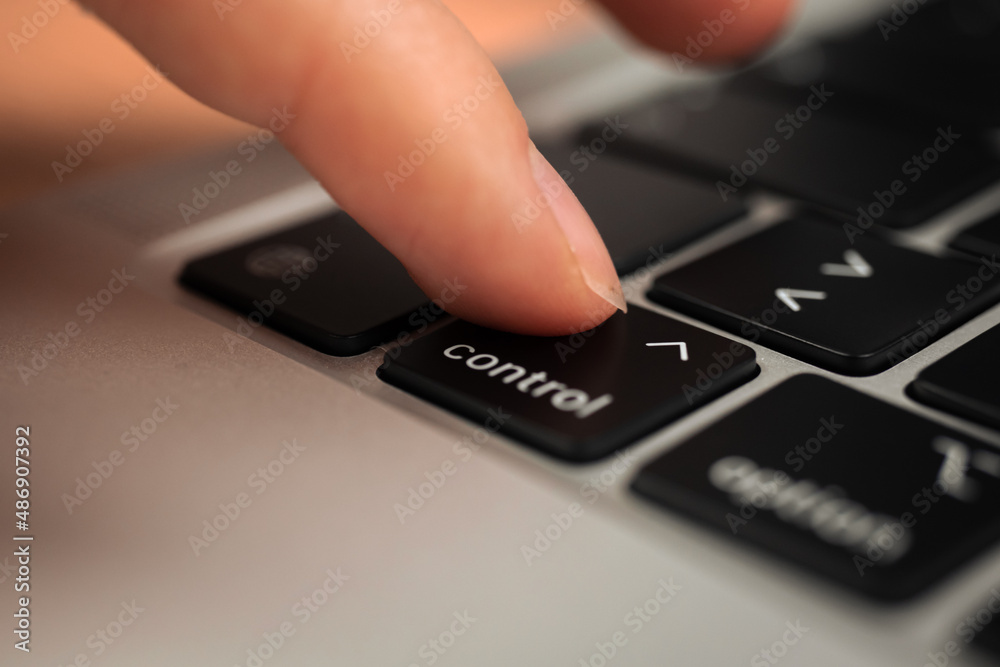 Hand pressing control key on modern laptop keyboard. Control sign and symbol close-up Hand pressing control key on modern laptop keyboard. Control sign and symbol close-up