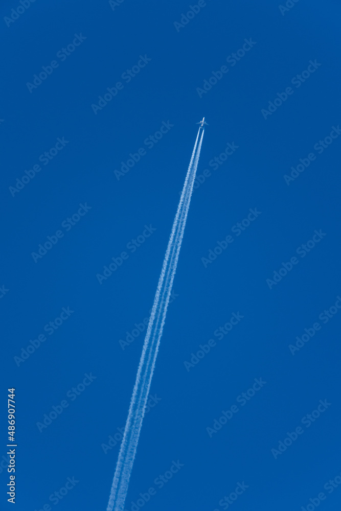 An airplane forming contrails in a blue sky An airplane forming contrails in a blue sky