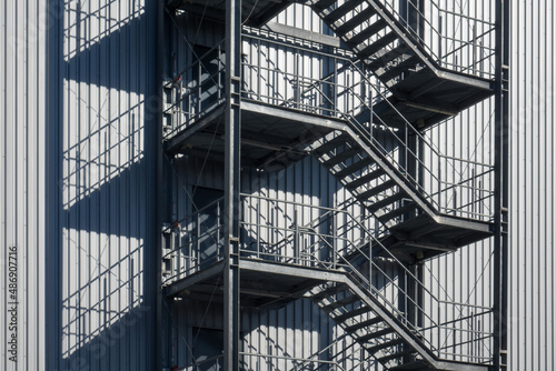 open fire escape staircase on the exterior wall of a warehouse with a corrugated sheet metal facade. 