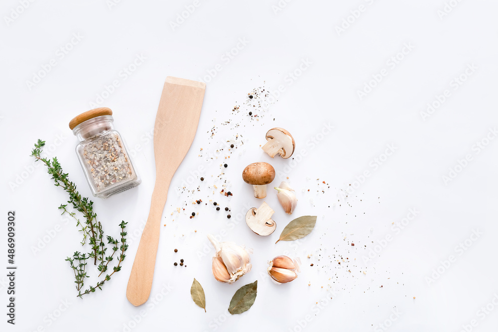 Wooden spatula with spices and vegetables on light grey background, top view. Wooden spatula with spices and vegetables on light grey background, top view.