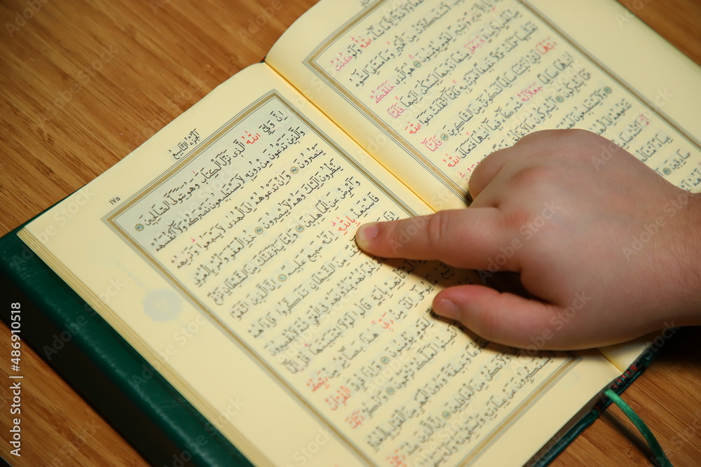 reading quran and pointing to word of allah with finger. photo