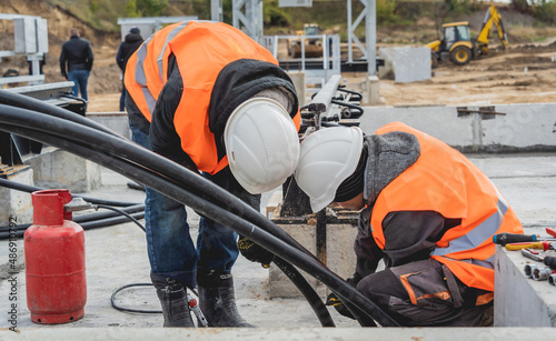 Two electrician builder workers installing high-voltage cable