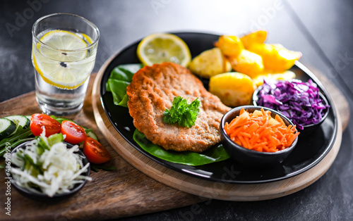 Pork cutlet coated with breadcrumbs with potatoes and salads