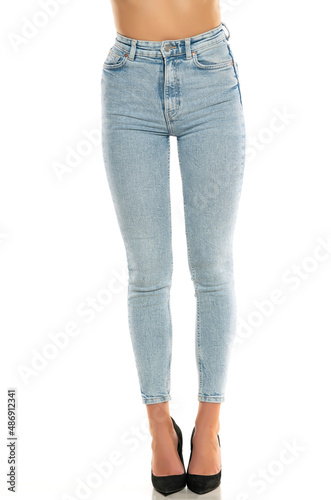 Front view of pretty female legs in jeans and shoes on white