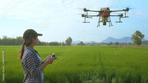 Young smart farmer controlling drone spraying fertilizer and pesticide over farmland,High technology innovations and smart farming photo