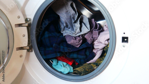 Close-up of a washing machine with the opened front door and clothes in it