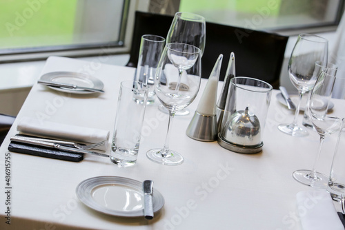 Beautifully set dinner table in a restaurant. Romantic fine dining table with cutleries, plates, wine glasses, napkins and naperies on the table. © AbdulRazak