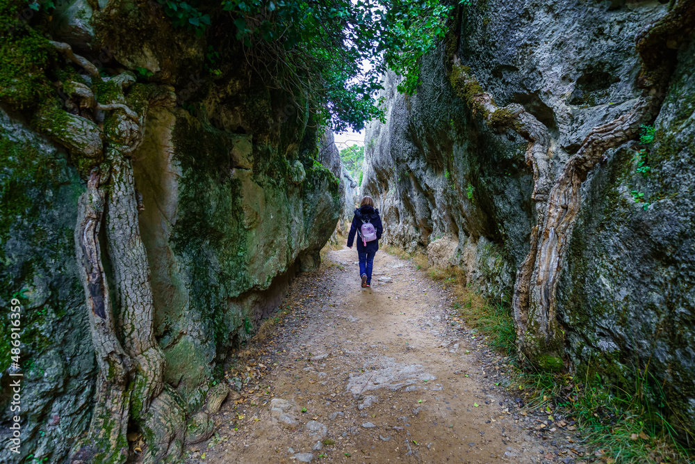 Woman walking backwards between large rock walls in the forest. Enchanted City Cuenca.