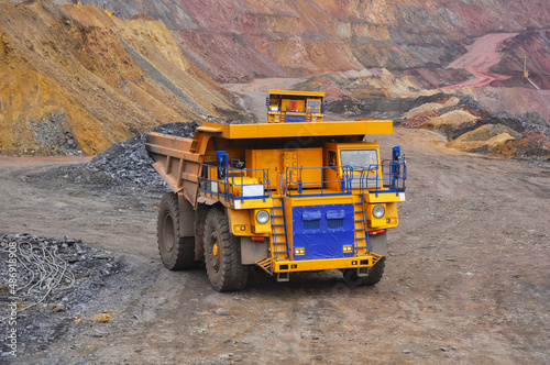 Extraction of iron ore. A mining dump truck transports iron ore along a side carrea. Special equipment works in a quarry