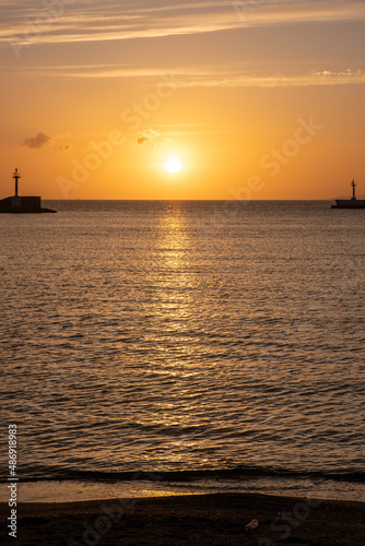 Sunset over Mykonos island  Cyclades  Greece. Lighthouse  orange yellow sky sparkle sea. Vertical