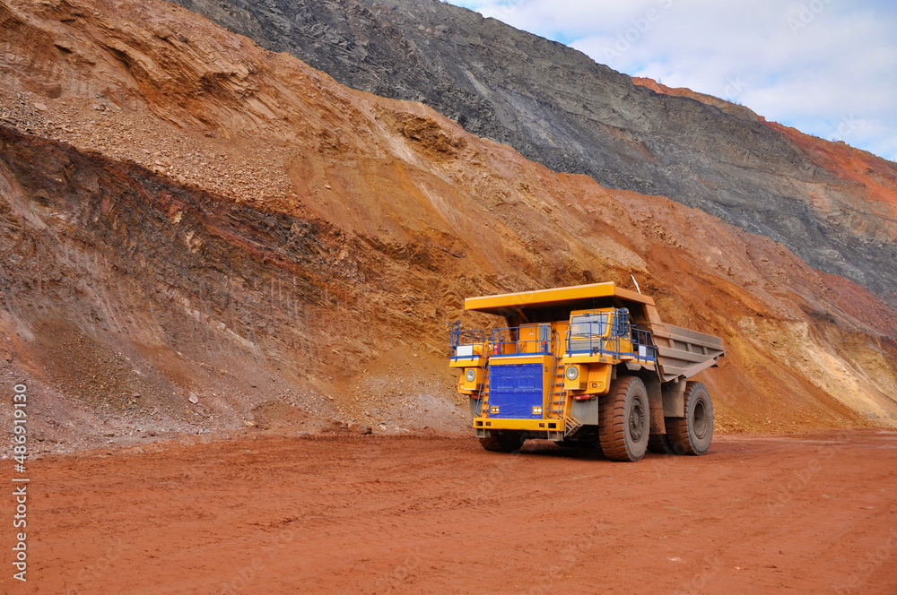 Extraction of iron ore. A mining dump truck transports iron ore along a side carrea. Special equipment works in a quarry Extraction of iron ore. A mining dump truck transports iron ore along a side carrea. Special equipment works in a quarry