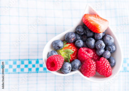 Woodberries in a white heart shaped bowl placed on a cloth photo