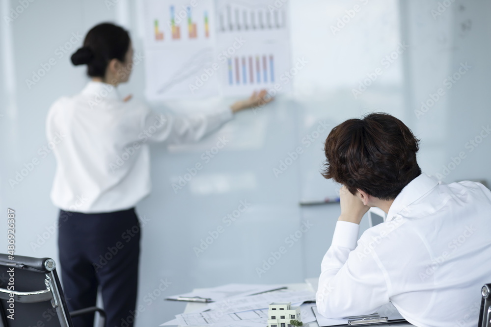 Fototapeta premium Businesswoman Explaining and Pointing at Chart on Board