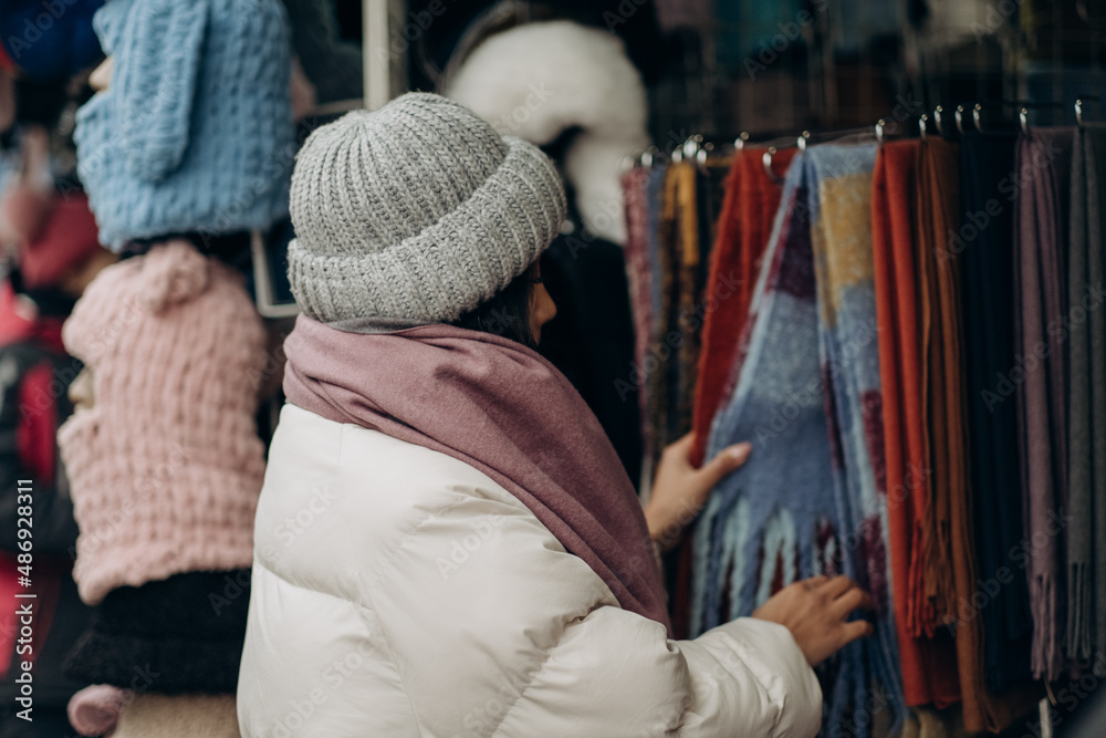 A young African American woman chooses a scarf at a street market.