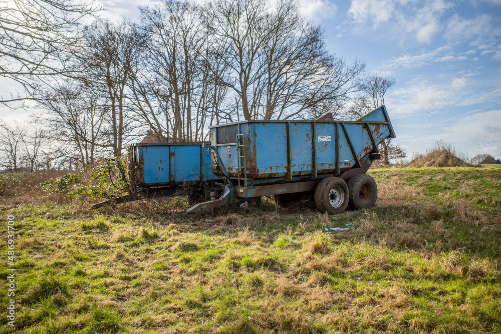 A pair of blue old and rusty trailers parked in an agricultural field in rural Norfolk