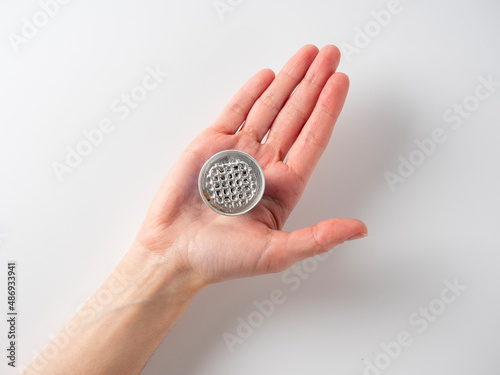 In the men's hand are one aluminum coffee capsules. One of the capsules is used. White background. Raw material reuse concept