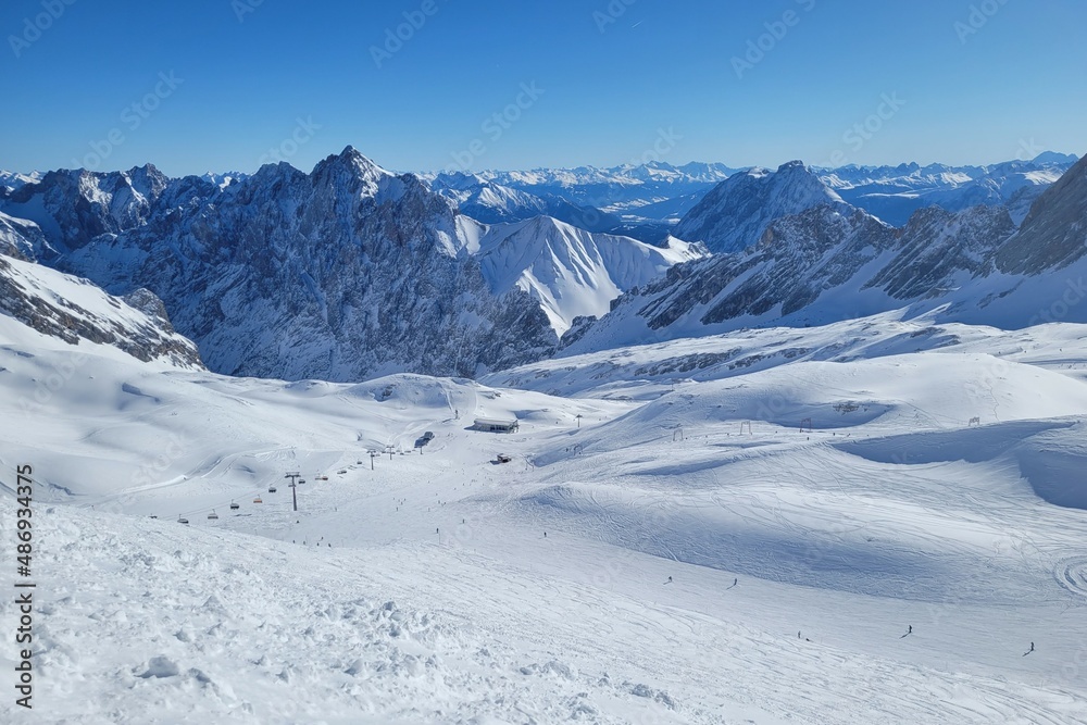 Panorama of ski resort in the german alps. Skiers on a slope on a sunny winter day.