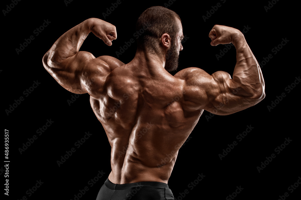 Muscular man showing back muscles, isolated on black background. Strong male rear view Muscular man showing back muscles, isolated on black background. Strong male rear view