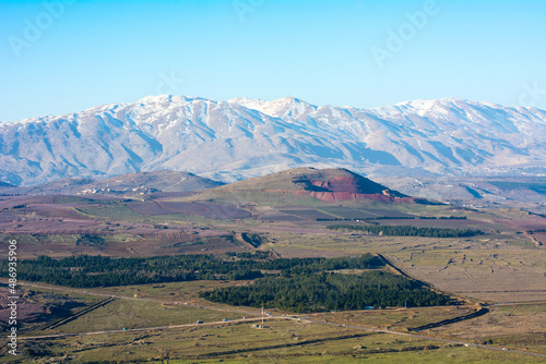 Mount Hermon in Israel in the winter with the Golan Heights beneath with roads and green fields. © TheYDP