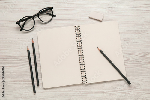 Flat lay composition with blank sketchbook on white wooden table. Space for text