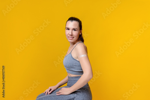 Caucasian middle-aged woman after vaccination against covid-19. Smiling woman with a band-aid on her arm after receiving a vaccine.