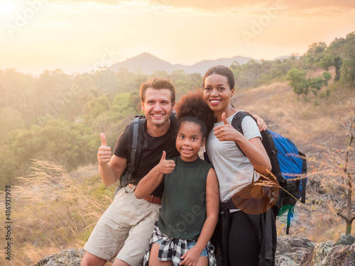 Happy diverse family, african and caucasian mom and dad with daughter enjoying at mountain camping. Travel, happiness and insurance concept.