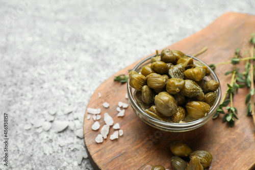 Tasty capers, salt and thyme on grey table, space for text
