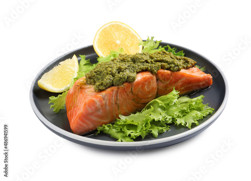Delicious cooked salmon with pesto sauce, lettuce and lemon on white background