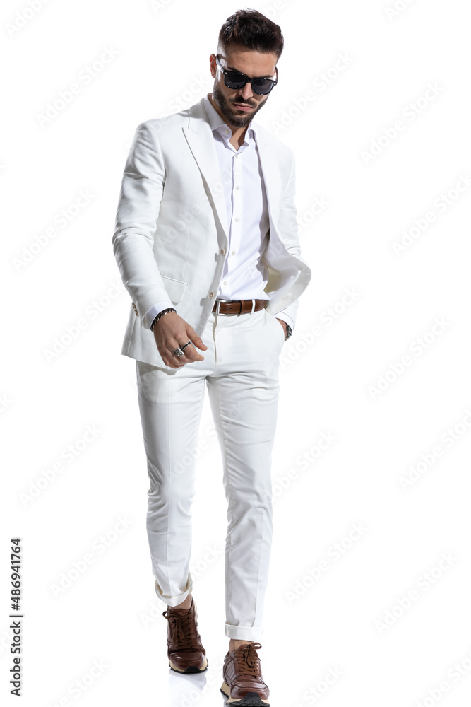 bearded young man with glasses looking down and holding hand in pocket bearded young man with glasses looking down and holding hand in pocket