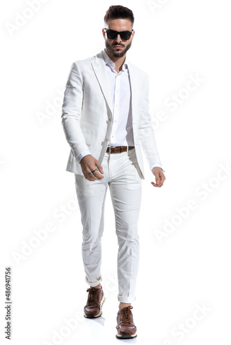 sexy businessman with glasses walking in a confident manner