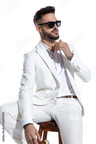 cool young businessman with sunglasses sitting on wooden chair