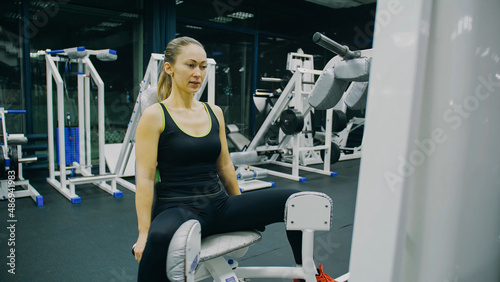 Fit Athletic Woman Girl Work out in Adduction Inner Thigh Machine, Doing Her Fitness Exercise. Muscular Women Training in Modern Gym. Sports People Workout in Adductor Exercising Fitness Center. photo