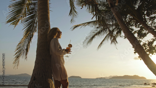 Photography SILHOUETTE DARK GOLD SUNSET VIEW: Sexy hot woman drinking pineapple cocktail Pina Colada near palm tree