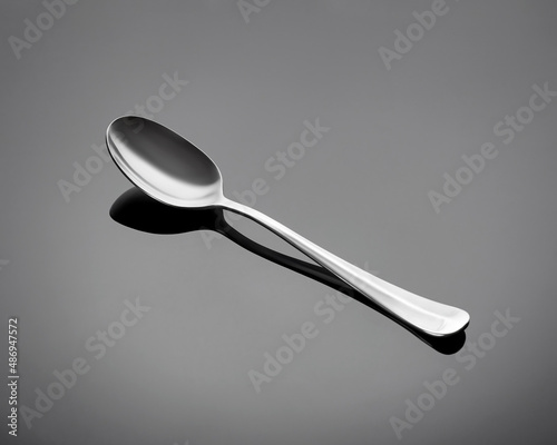 Table spoon on a gray glossy background. Spoon is arranged diagonally.