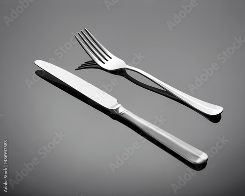 Cutlery set - table knife and fork on a gray glossy background. Cutlery is arranged diagonally.