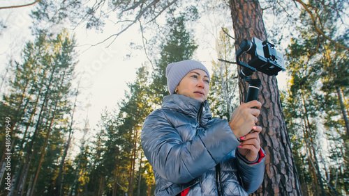 The Woman Professional Videographer Holding Smartphone on 3-axis Gimbal Stabilization Device in Winter. Pro Equipment Helps to Make High Quality Video on Phone. Cinematographer Operator. Slow Motion